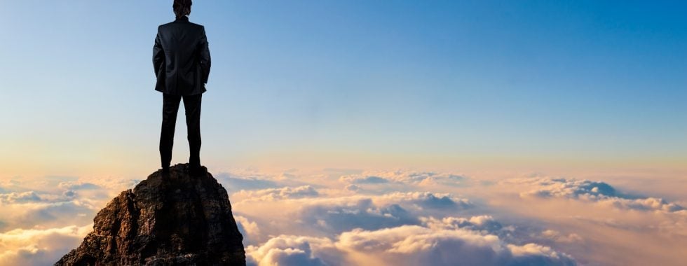 a person standing on a cliff above the clouds